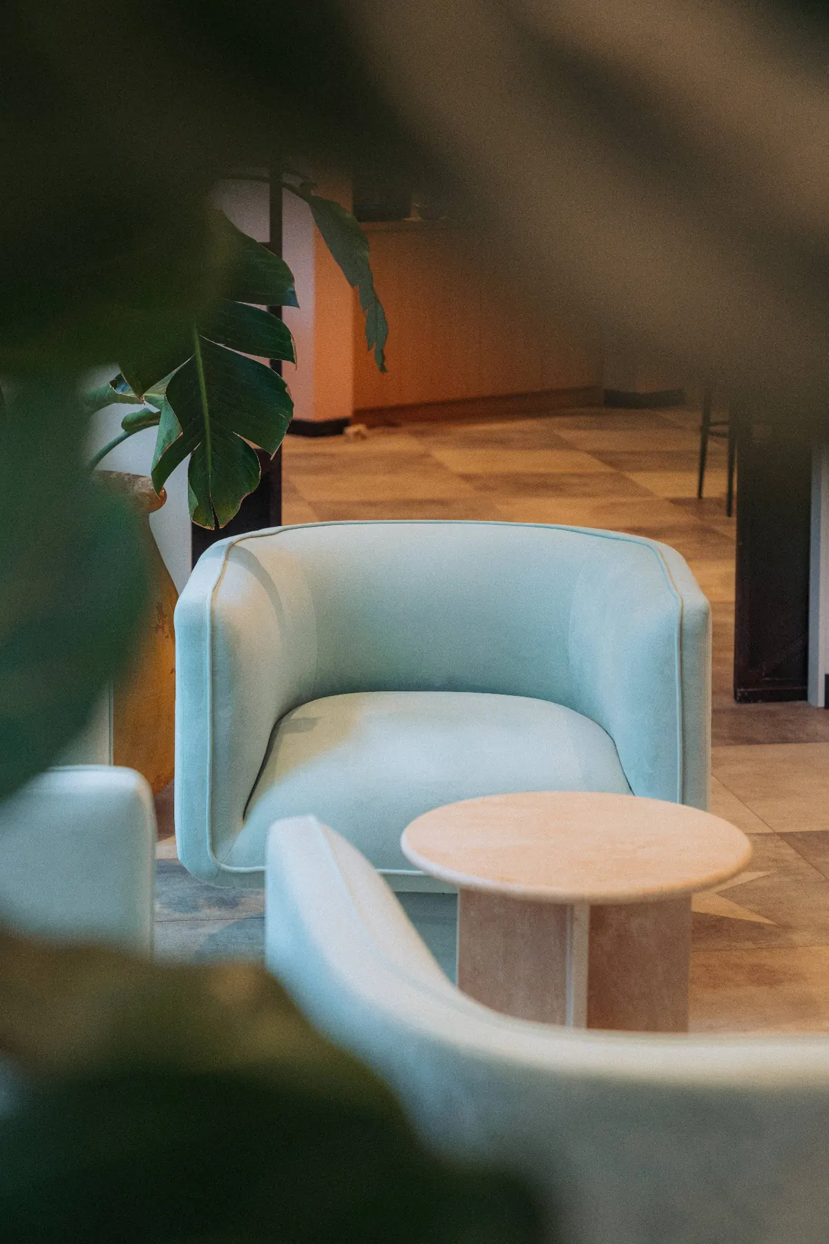 Fauteuil vert d'eau et table travertin dans le salon du The Cannes Motel