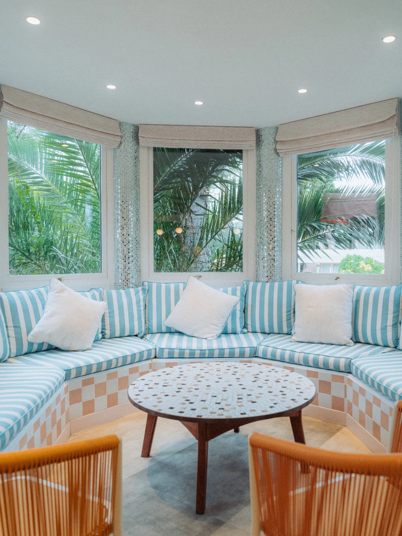 Salon rotonde avec banquette rayée bleu et table mosaïque du The Cannes Motel